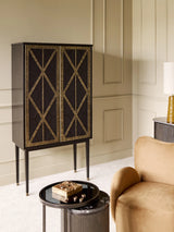 Black and gold bar cabinet in elegant living room with beige walls and plush armchair.