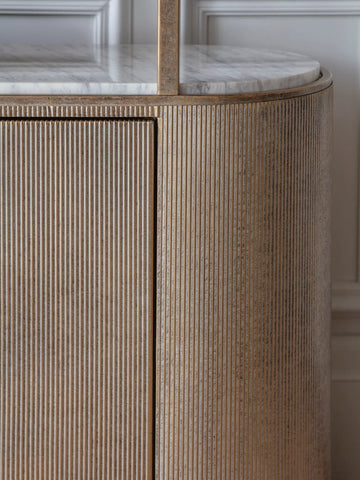 Ribbed aged gold shelving unit with marble top detail.