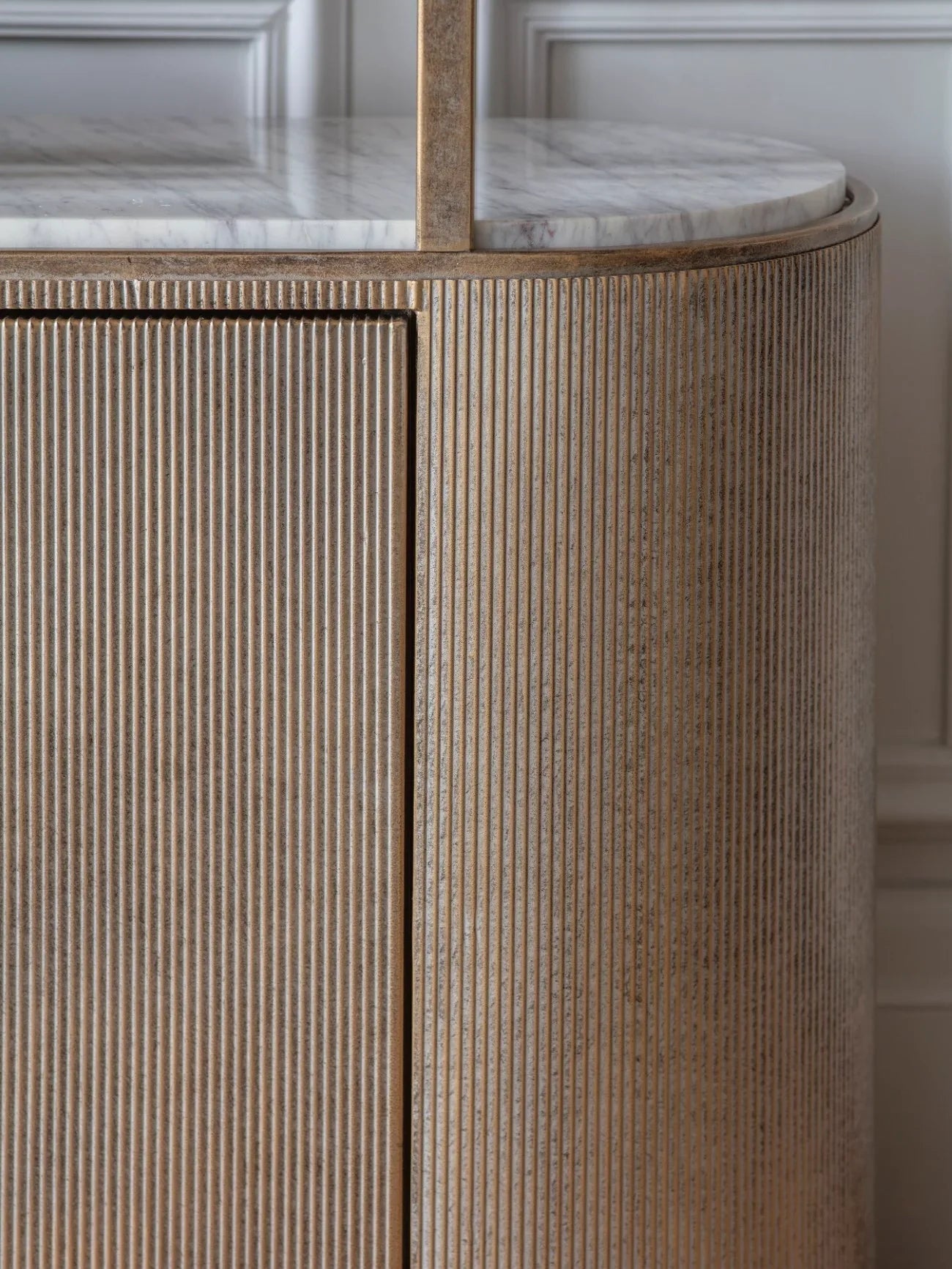 Ribbed aged gold shelving unit with marble top detail.