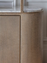 Ribbed aged gold shelving unit with marble top detail.