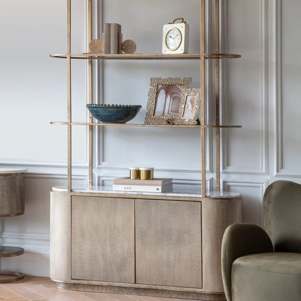 Aged gold shelving unit with storage in elegant living room setting.