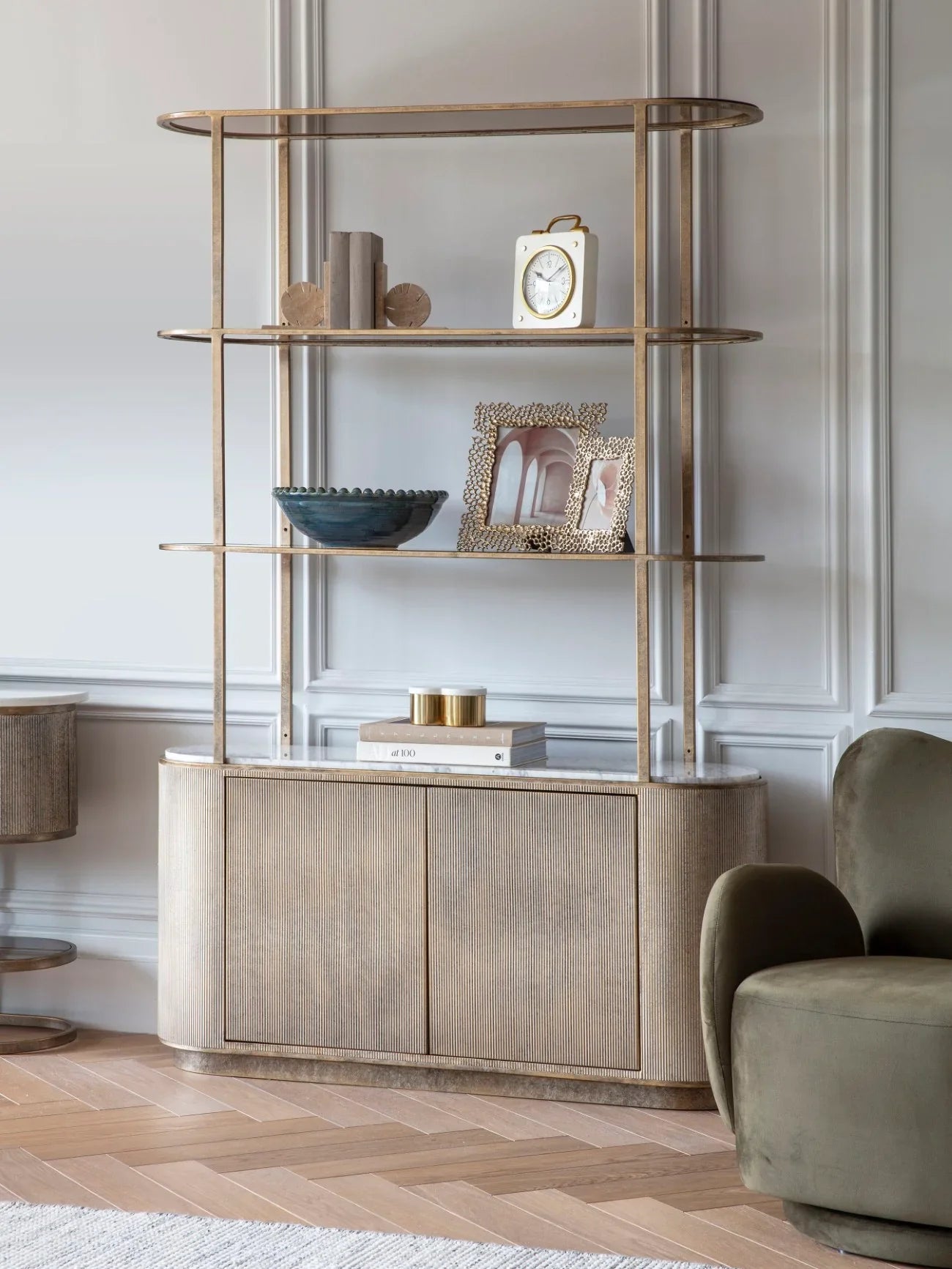 Aged gold shelving unit with storage in elegant living room setting.