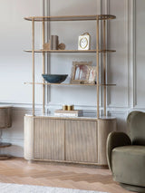 Aged gold shelving unit with storage in elegant living room setting.