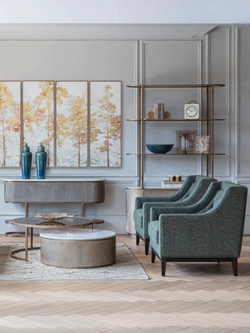 Aged gold shelving unit in elegant living room with teal armchairs.