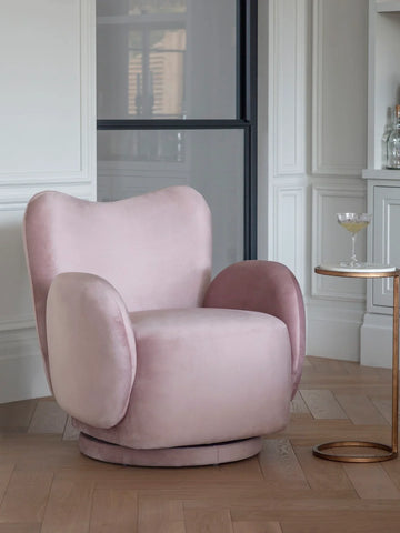Dusky pink velvet swivel chair in elegant living room with side table.