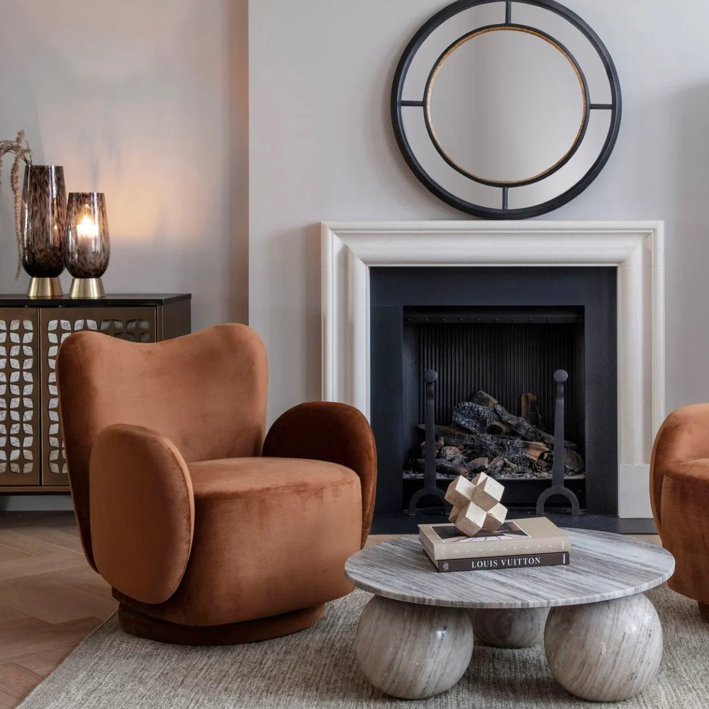Round marble coffee table in elegant living room with plush armchairs.