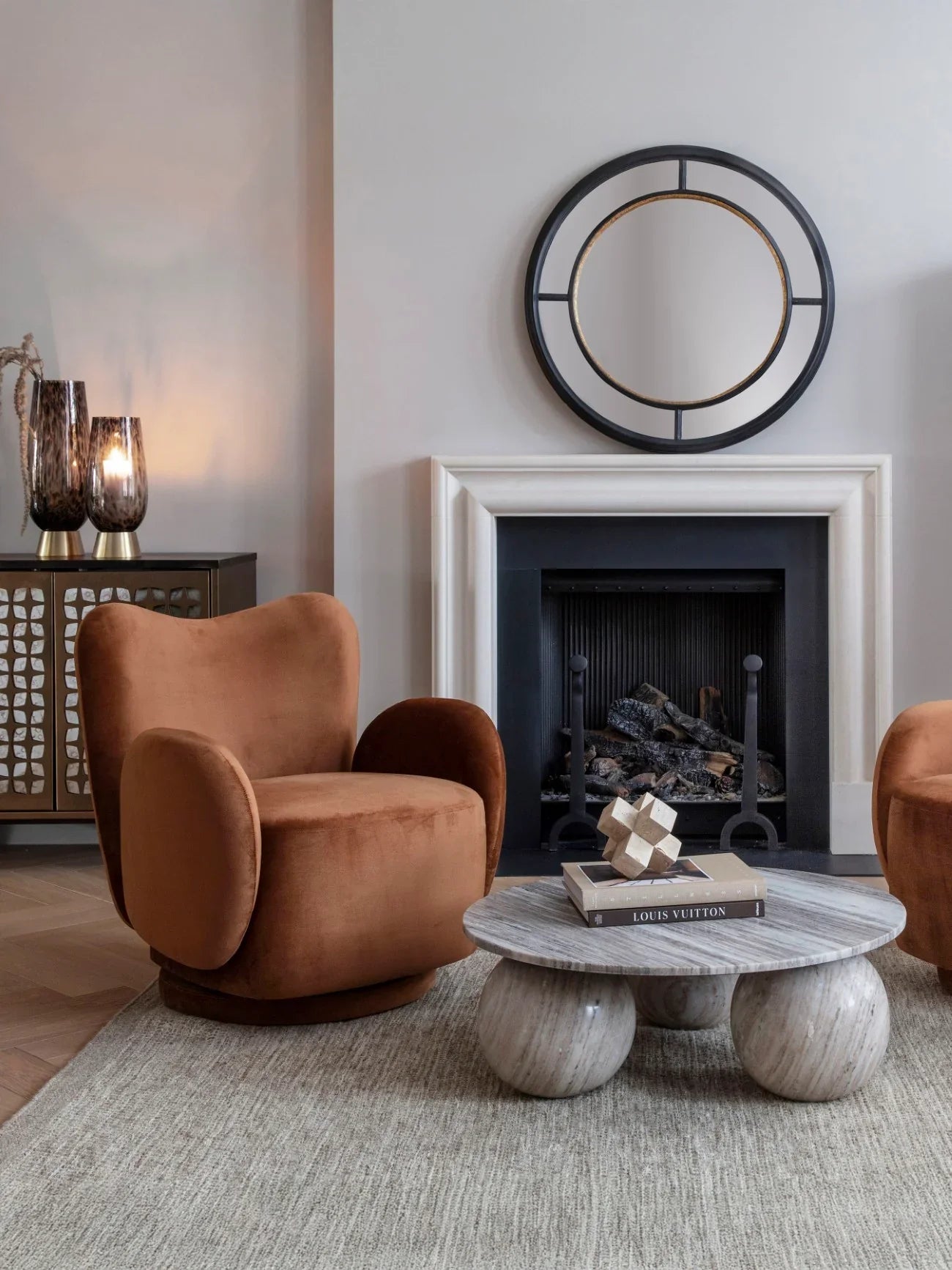 Round marble coffee table in elegant living room with plush armchairs.