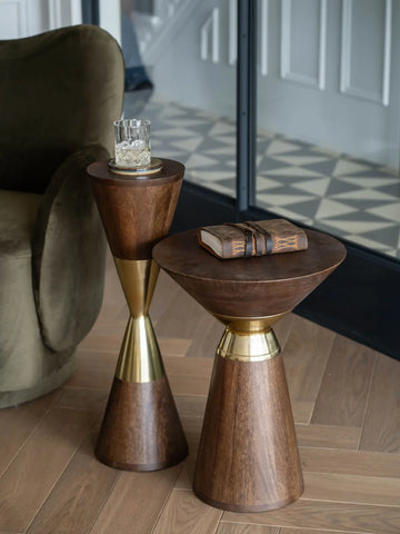 Wooden side tables with brass accents beside a green armchair.