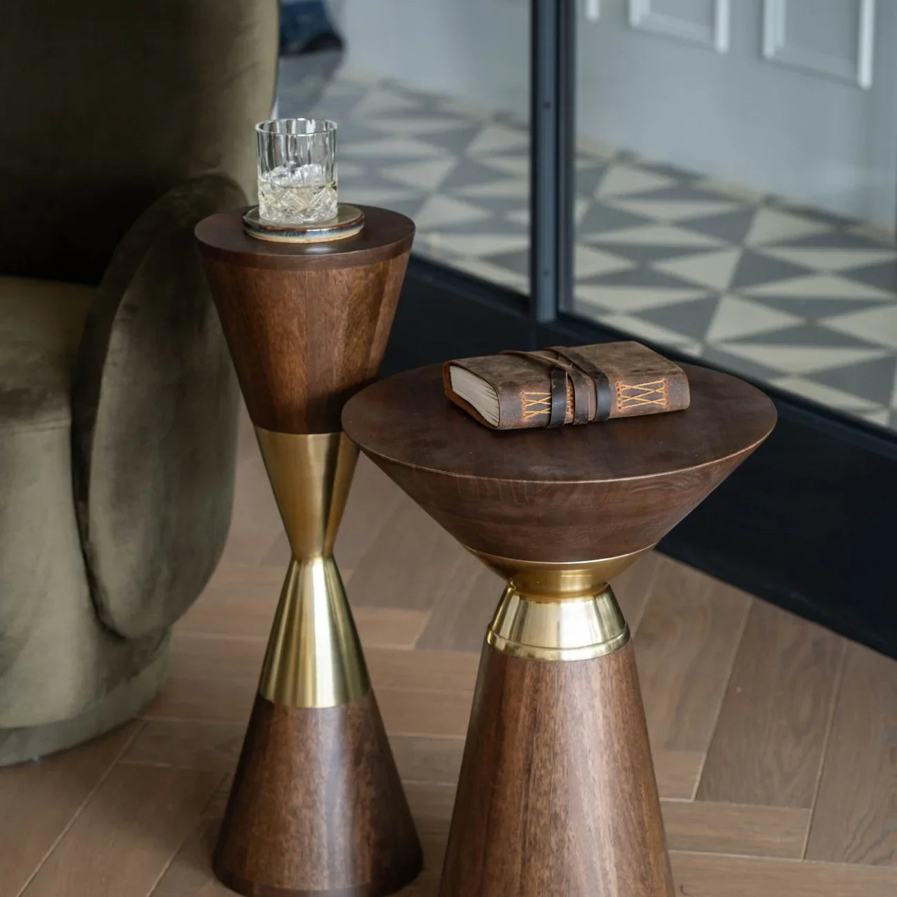 Dark wooden tables with brass accents, styled with a glass and notebook.
