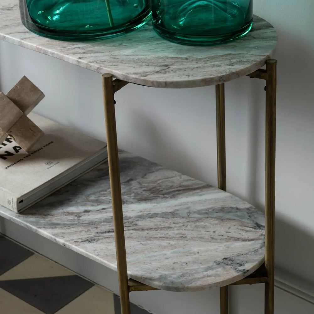 Marble console table with brass legs, green glass vases, and books.