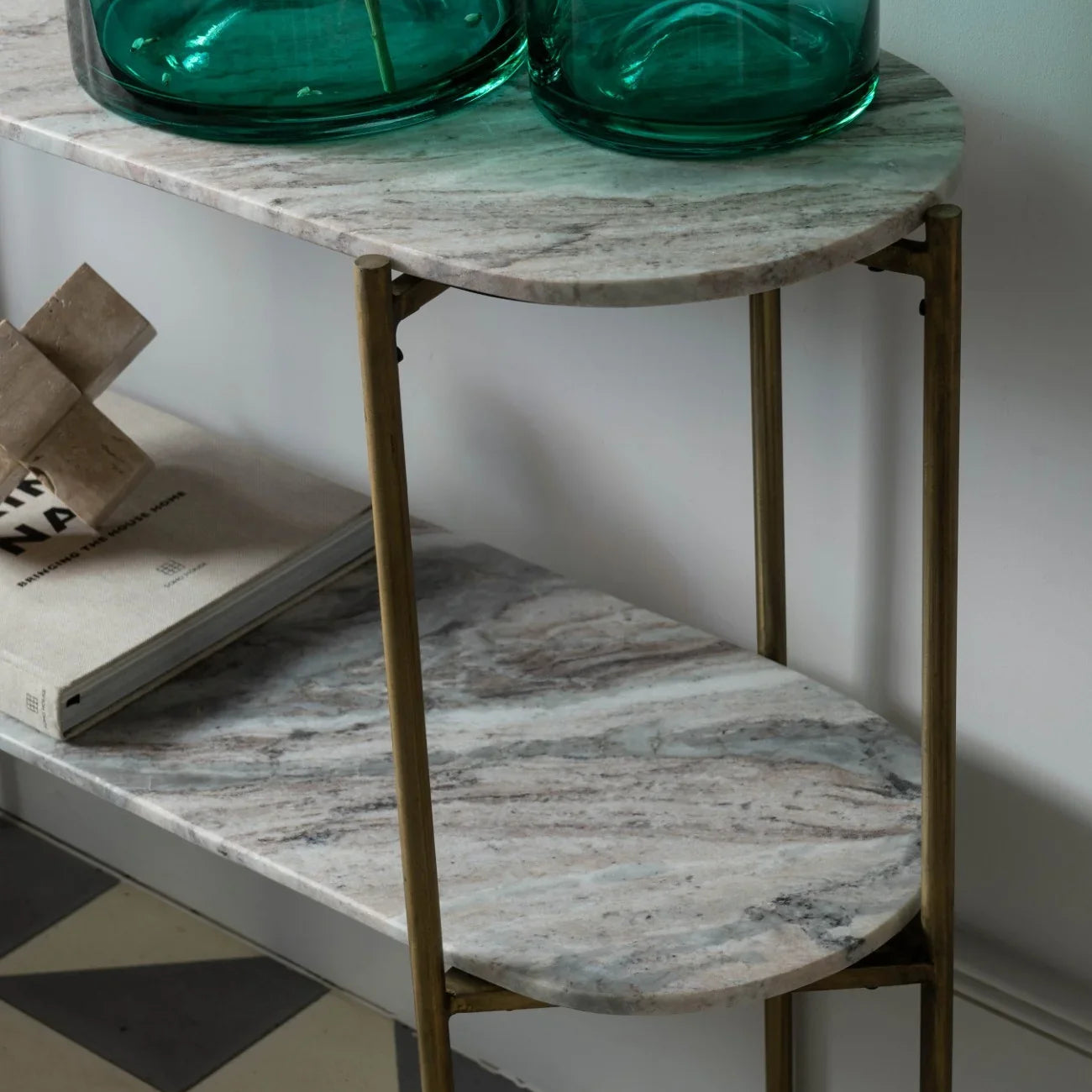 Marble console table with brass legs, green glass vases, and books.