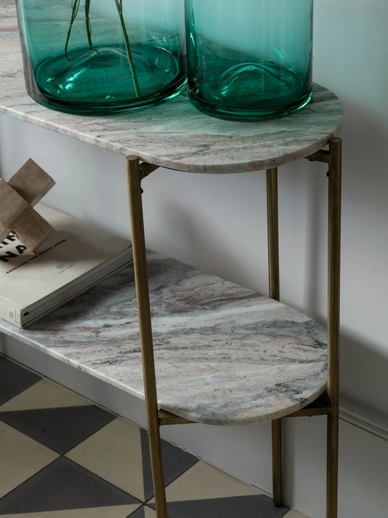 Marble console table with brass legs, green glass vases, and books.