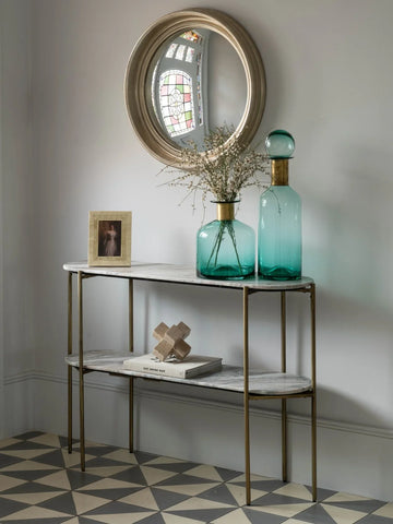 Console table with marble top in hallway, styled with teal vases and round mirror.