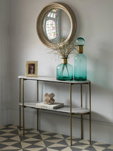 Console table with marble top in hallway, styled with teal vases and round mirror.
