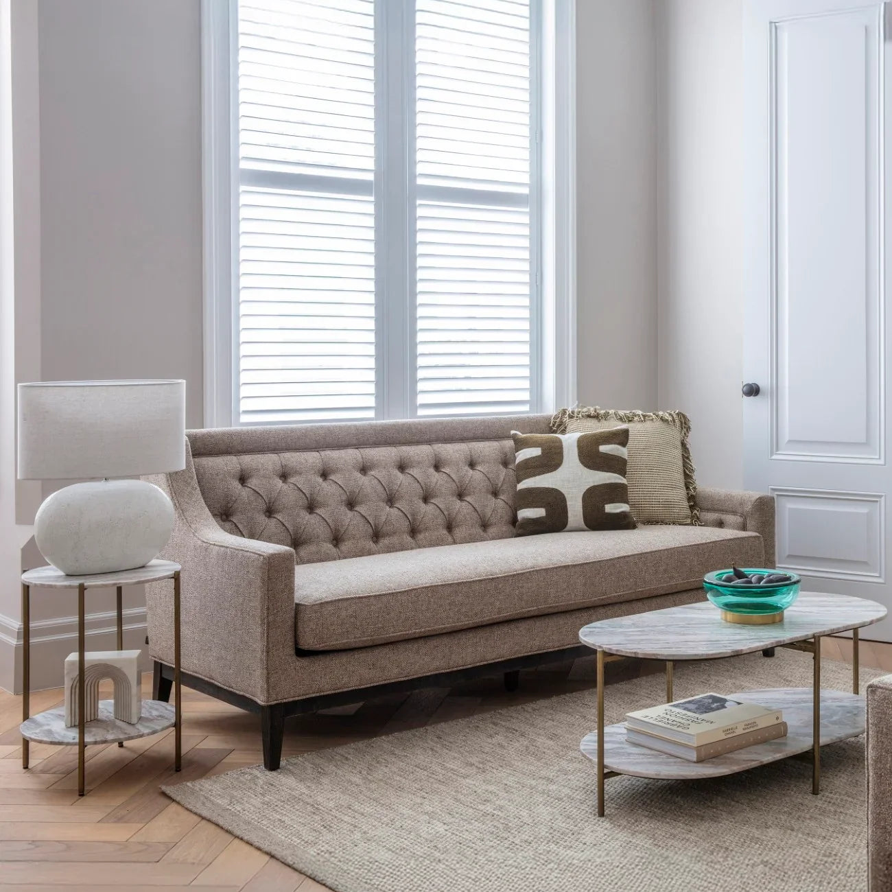 Modern side table in a cozy living room with a beige sofa and large windows.