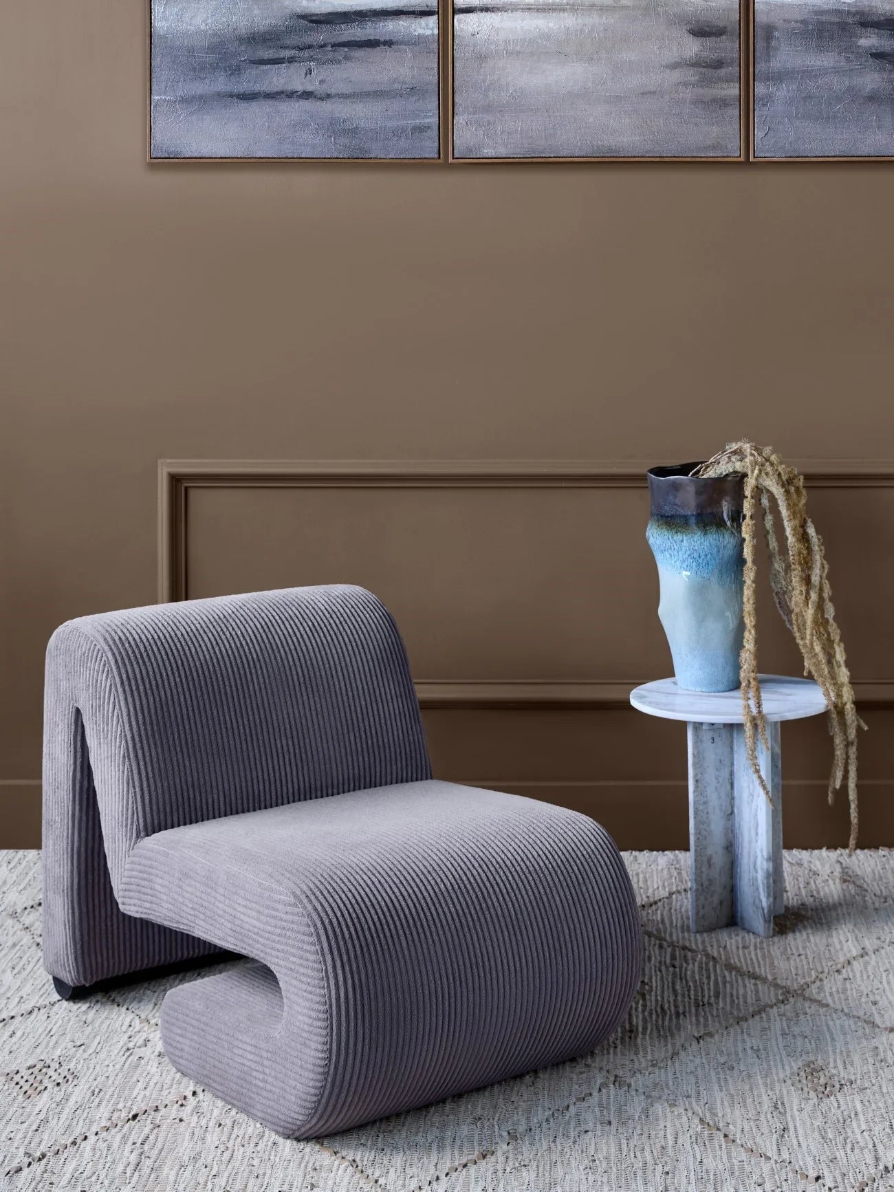 Corduroy chair in a cozy room with a side table and abstract wall art.