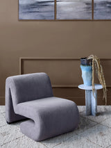 Corduroy chair in a cozy room with a side table and abstract wall art.