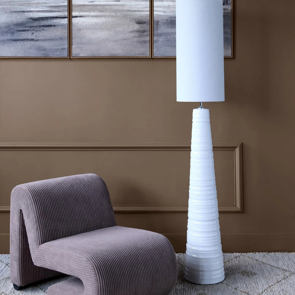 Curved brown corduroy chair with white floor lamp in modern living room.