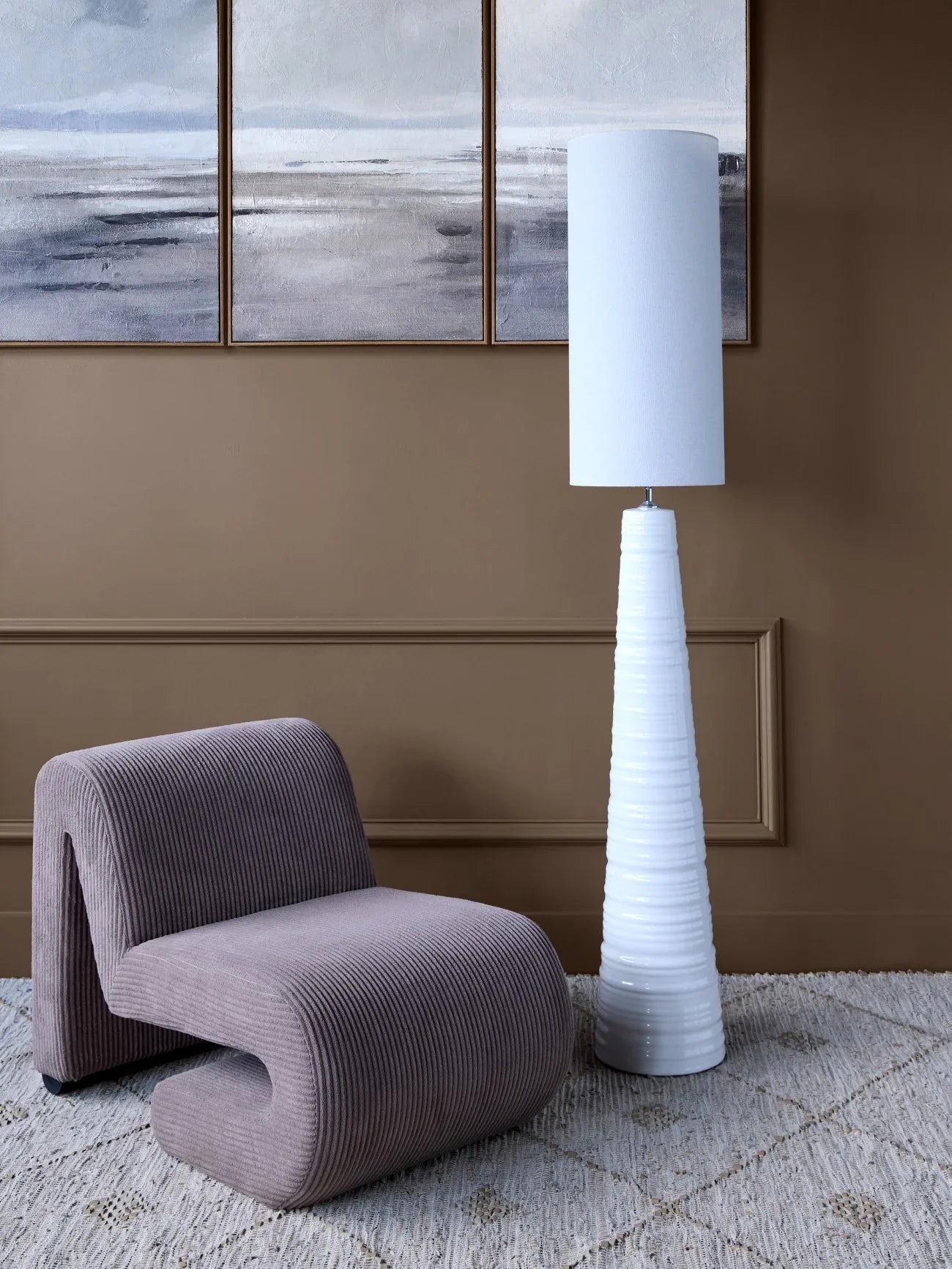Curved brown corduroy chair with white floor lamp in modern living room.