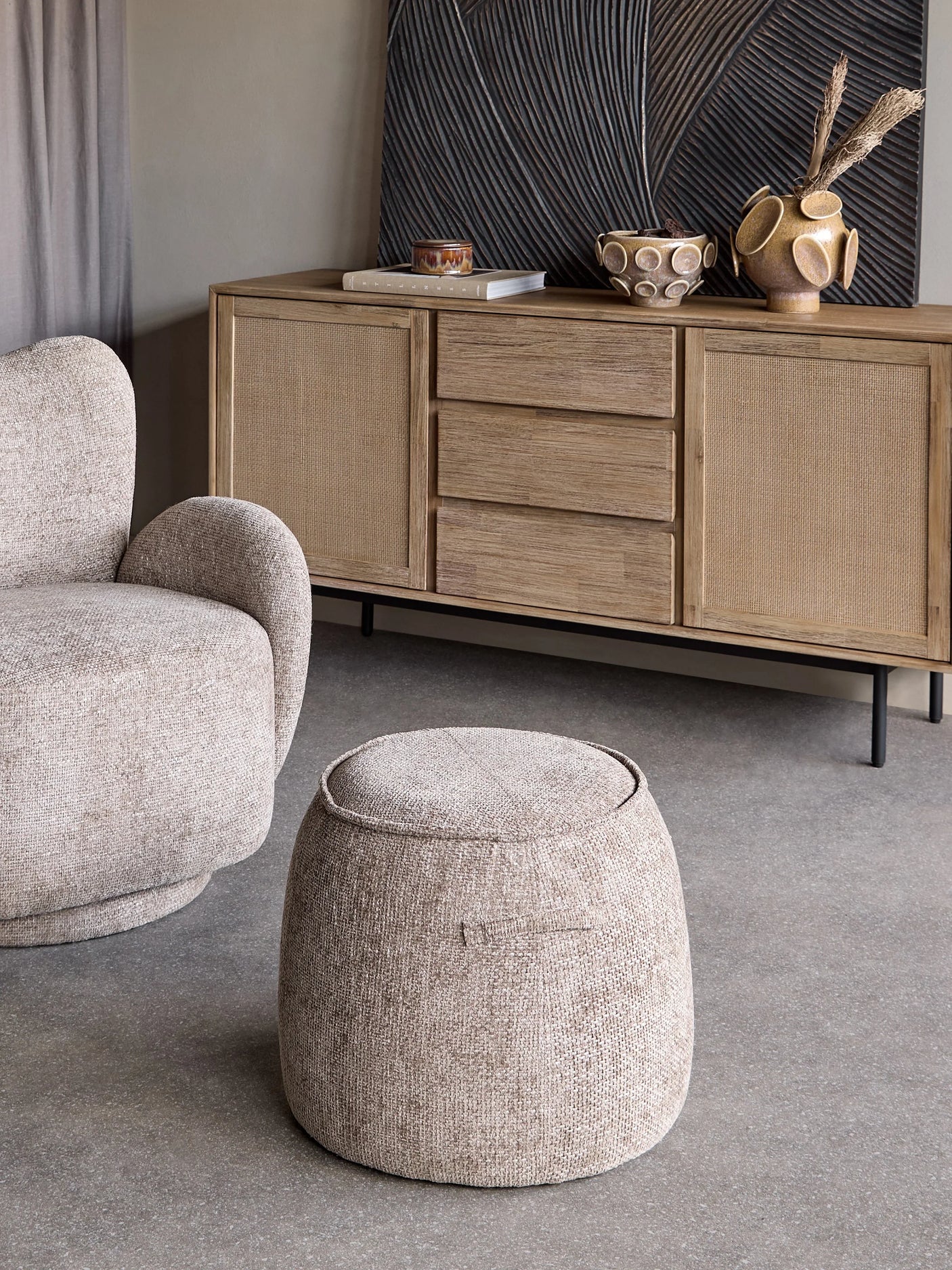 Beige textured stool in a cozy living room with a wooden sideboard.