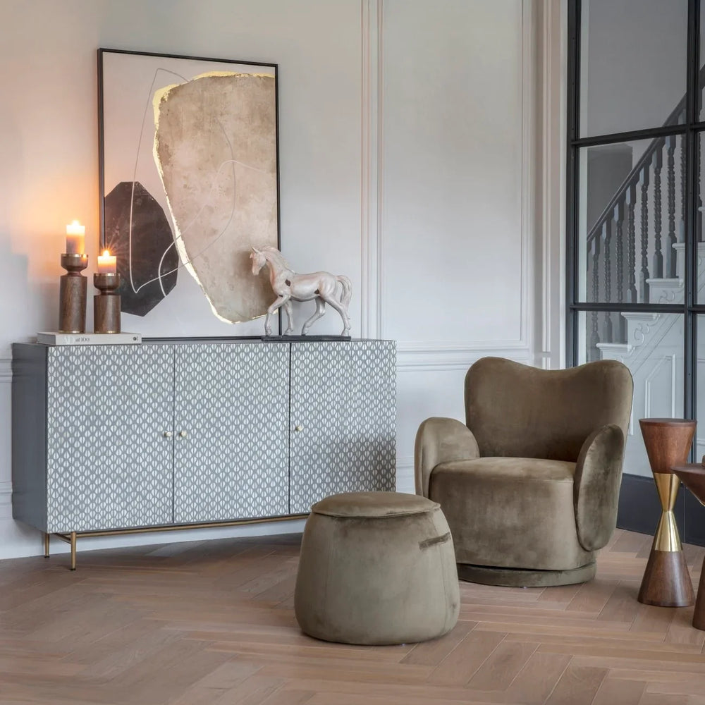 Velvet green stool in elegant living room with armchair and sideboard.