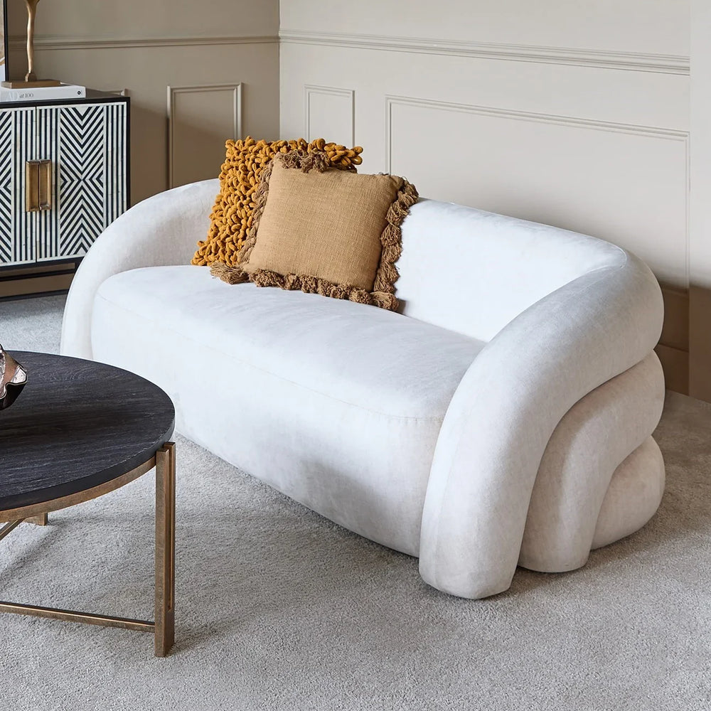 Cream two-seater sofa with mustard cushions in an elegant living room setting.