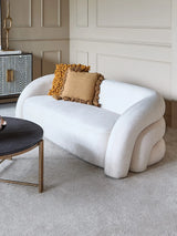 Cream two-seater sofa with mustard cushions in an elegant living room setting.