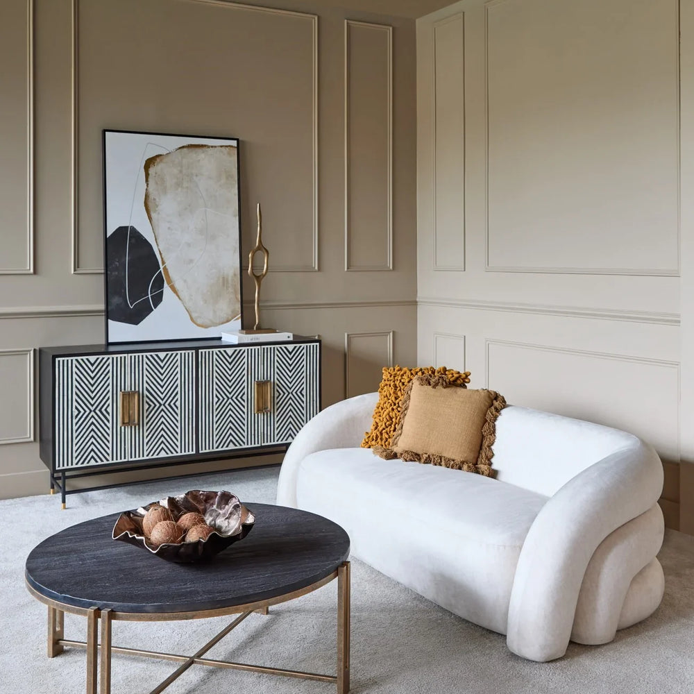 Cream two-seater sofa in elegant living room with patterned sideboard.