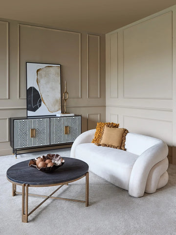 Cream two-seater sofa in elegant living room with patterned sideboard.
