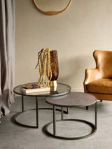 Glass and metal nesting tables in a cozy living room with leather chair.