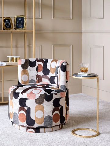 Patterned swivel chair in a cozy room with a gold side table and shelf.
