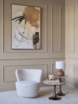 Textured natural swivel chair in elegant living room with abstract art.