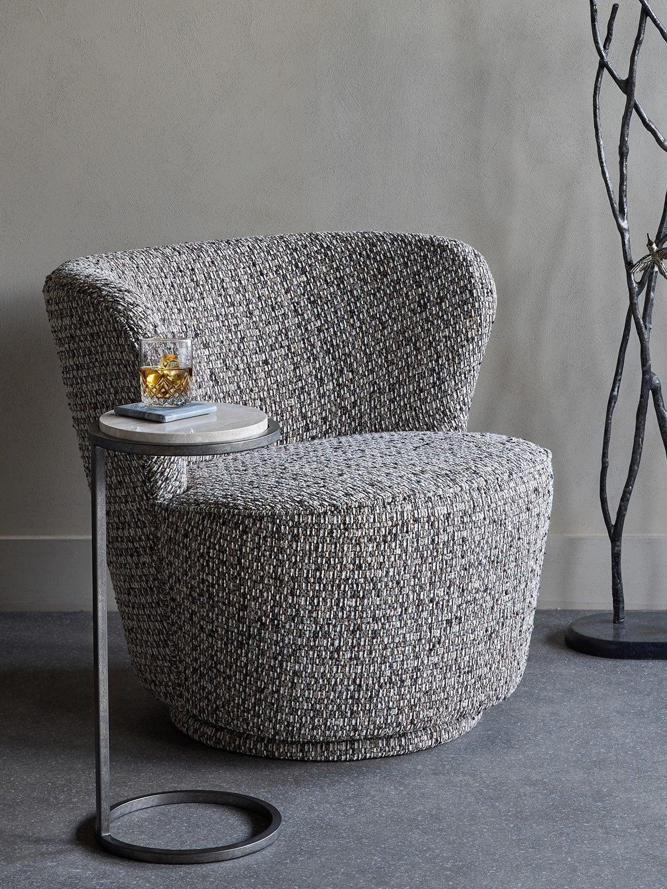 Mocha textured chair beside a small round table with a drink in a modern room.