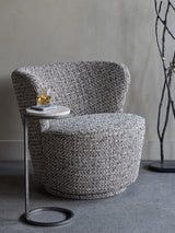 Mocha textured chair beside a small round table with a drink in a modern room.