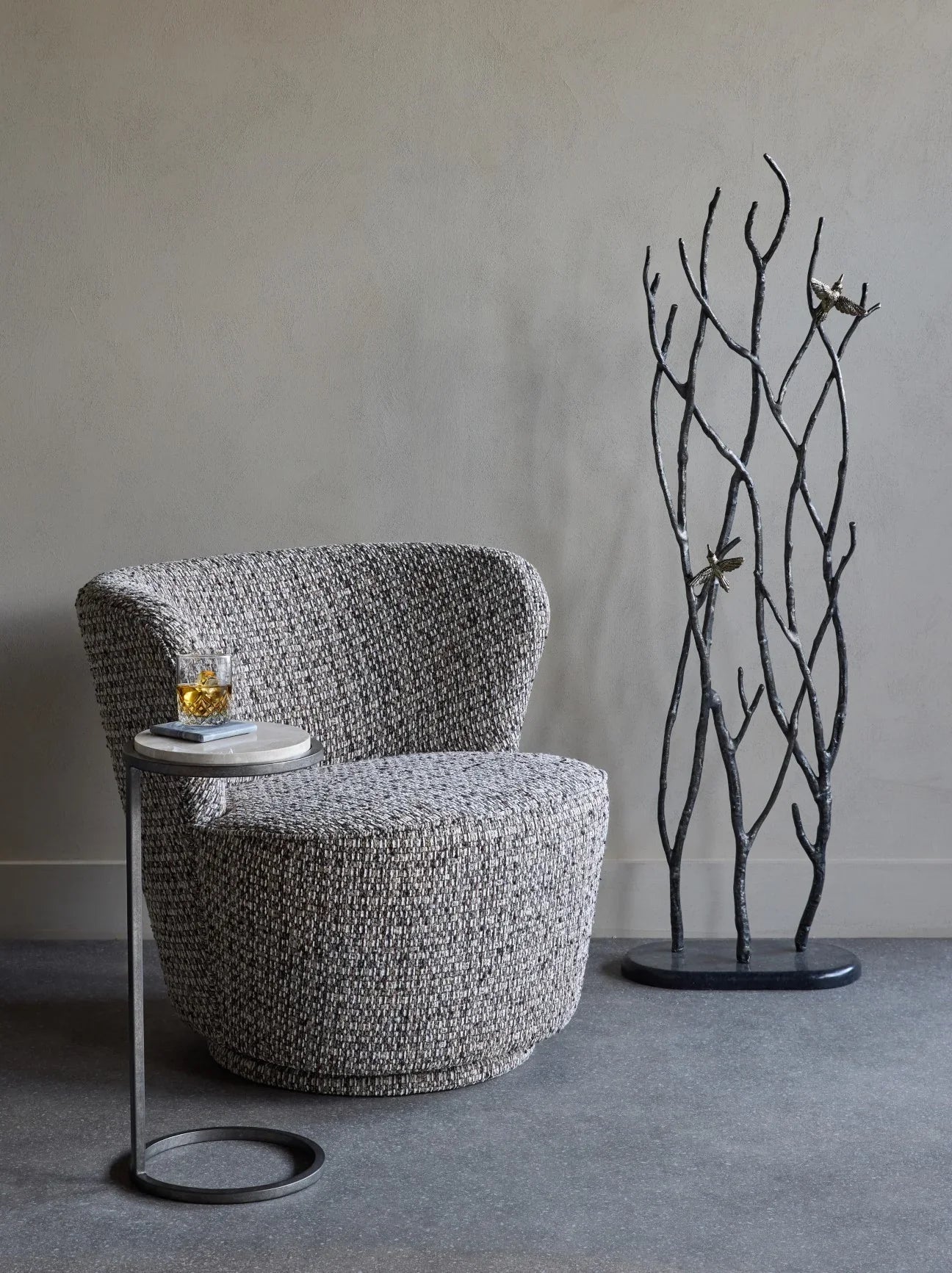 Mocha textured swivel chair with side table and decorative branches.