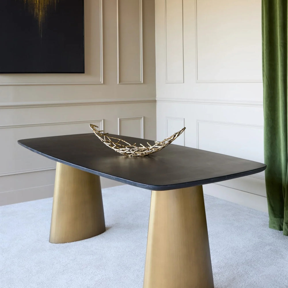 Black marble dining table with brass legs in elegant room setting.