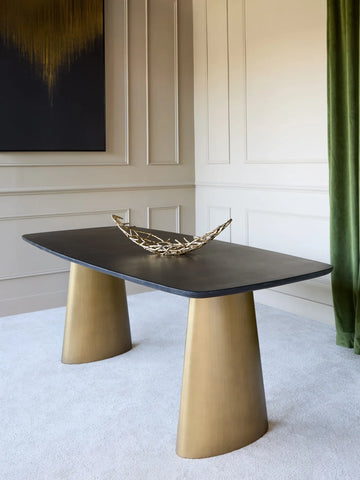 Black marble dining table with brass legs in elegant room setting.