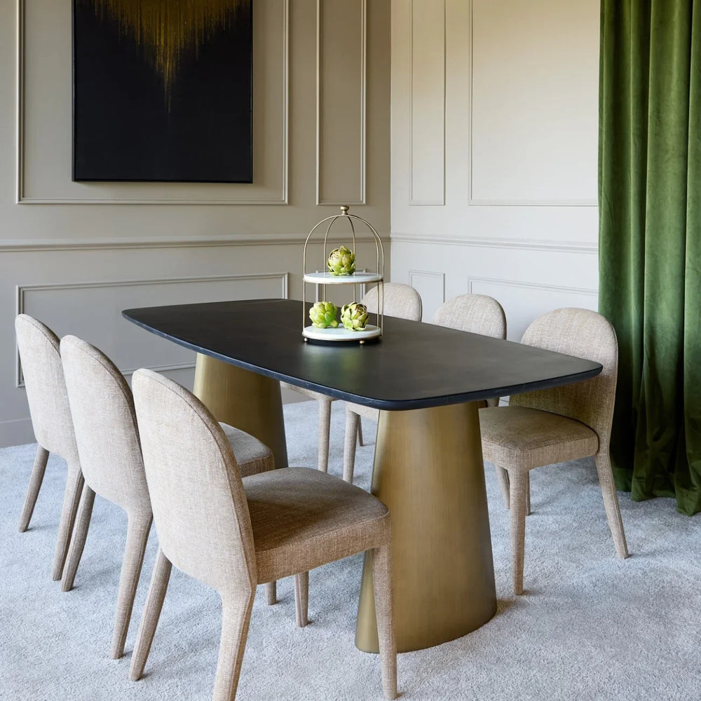 Black marble dining table with brass legs in elegant dining room setting.