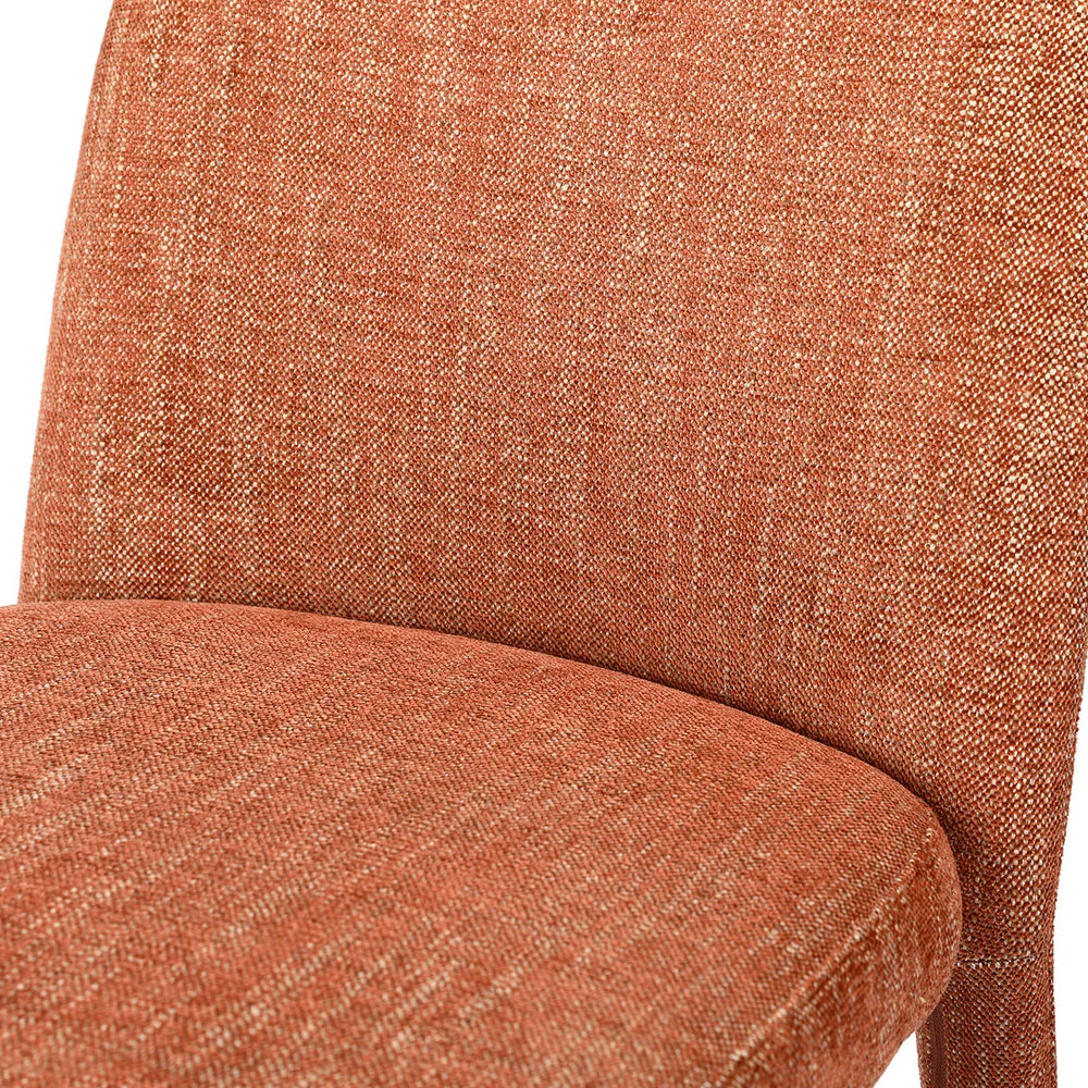 Rust-colored fabric dining chair with textured upholstery detail.