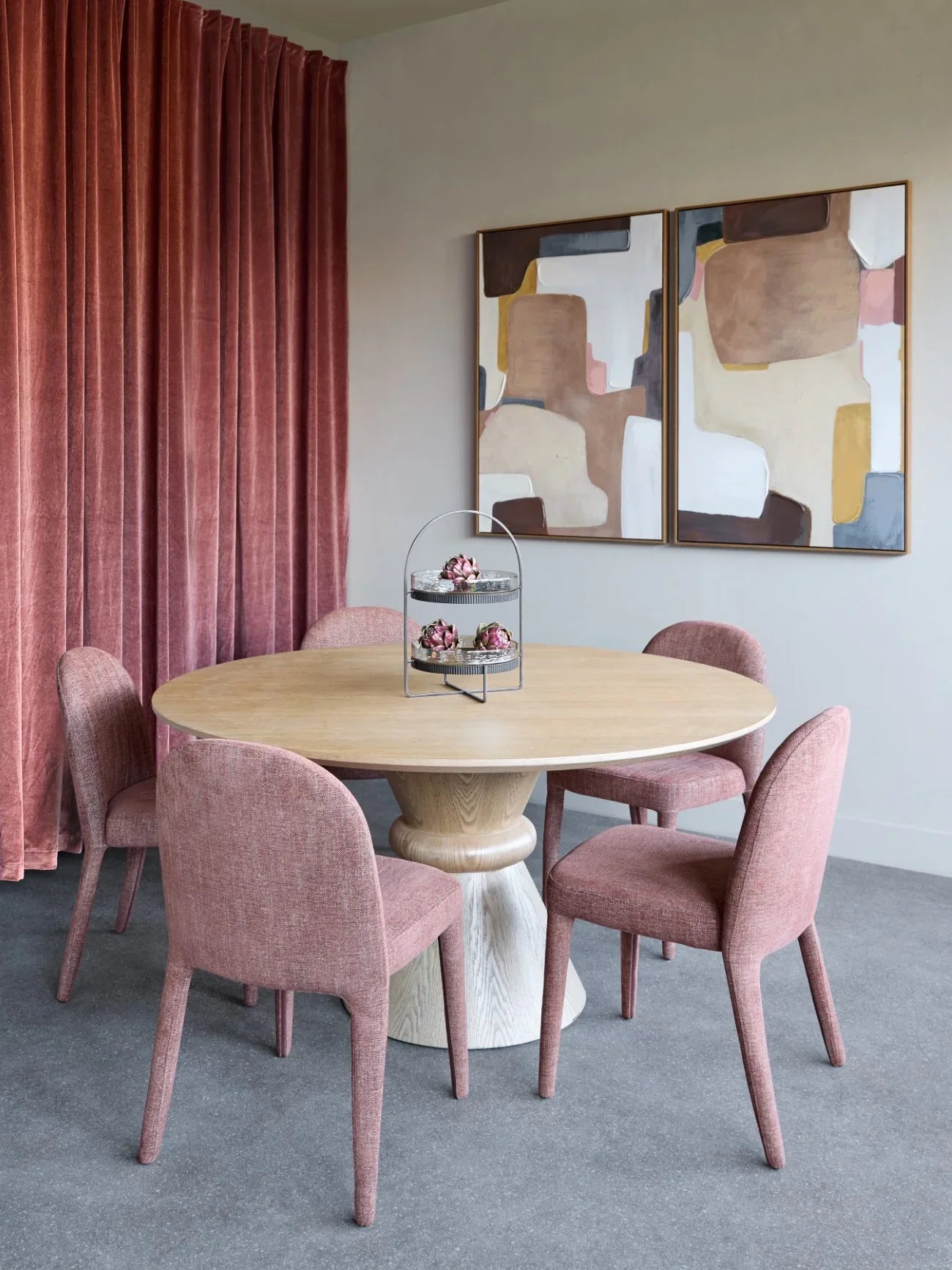 Dining chairs in a modern room with abstract art and pink curtains.