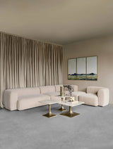 Beige sectional sofa in elegant living room with marble tables.
