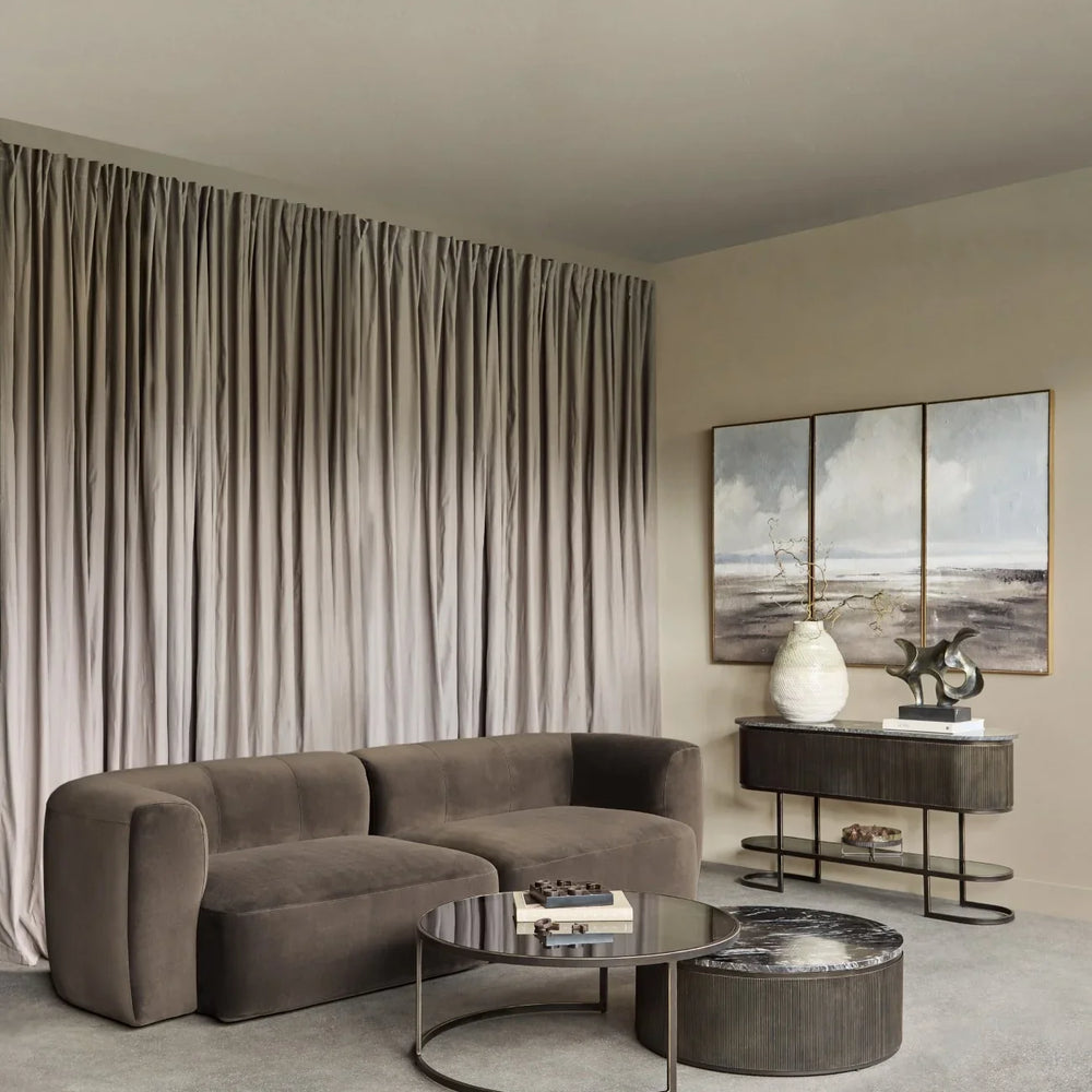 Brown velvet sofa in elegant living room with modern decor and soft drapes.