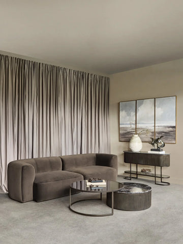 Brown velvet sofa in elegant living room with modern decor and soft drapes.