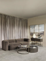Brown velvet sofa in elegant living room with modern decor and soft drapes.