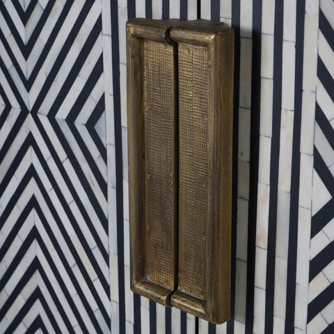 Brass handle on geometric black and white inlay pattern.