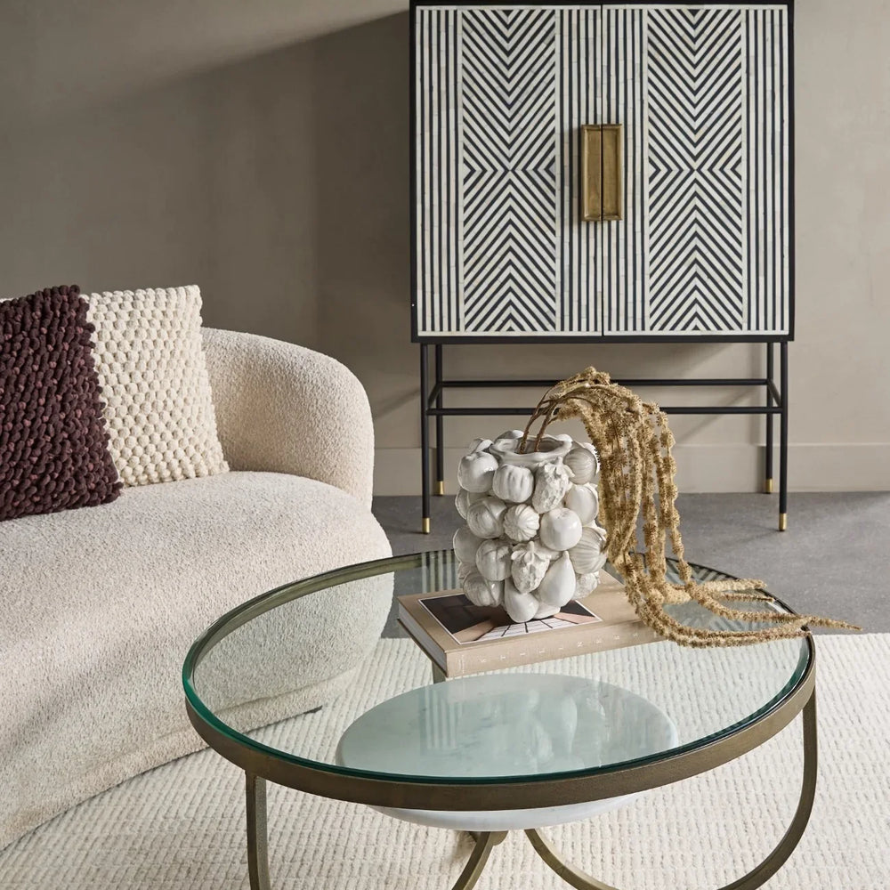 Black and white patterned cabinet in a modern living room with a glass coffee table.