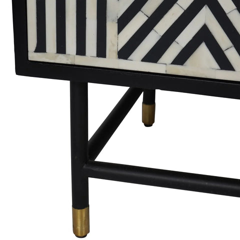 Black and white geometric pattern with gold-tipped legs on cabinet corner.