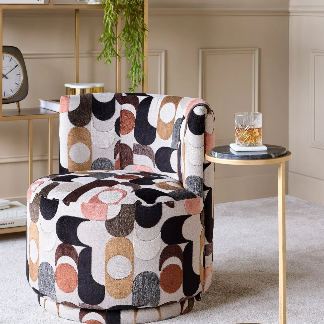 Black marble table with gold frame beside patterned chair in elegant living room.
