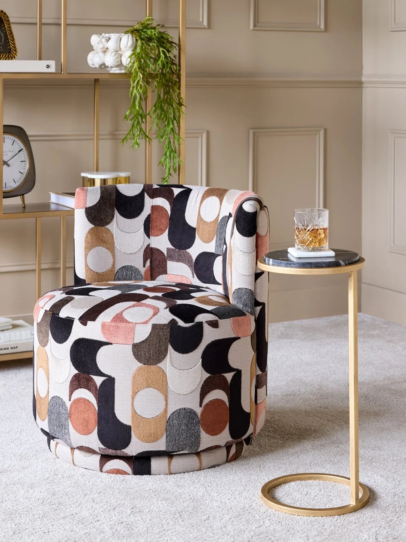 Black marble table with gold frame beside patterned chair in elegant living room.