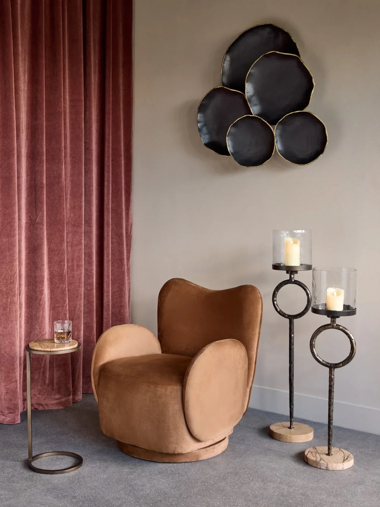 Brown marble side table beside plush chair and tall candle holders in elegant room.